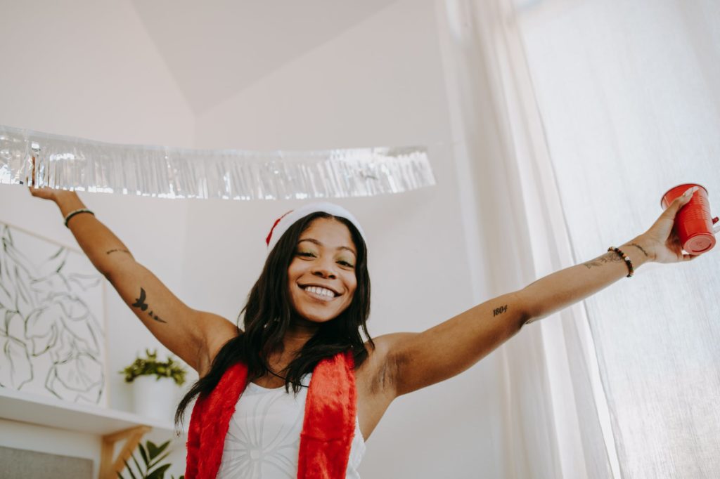 a low angle shot of a woman raising her hands while holding a red cup